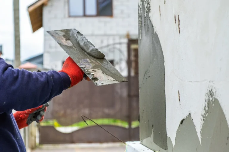 construction worker applies smoothness to a external wall