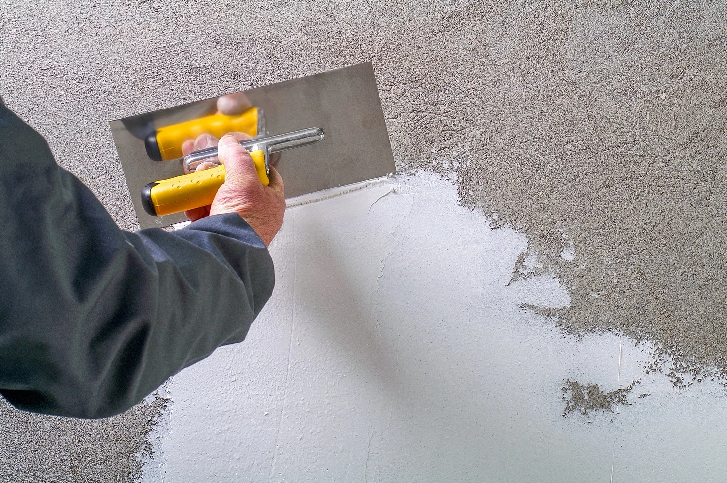 construction worker applies smoothness to a external wall